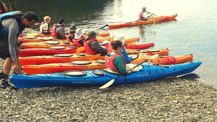 People on the ground, adjusting their kayaks before launching.