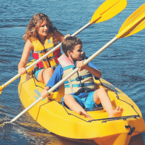 Brother and sister having fun in a sit-on-top kayak.