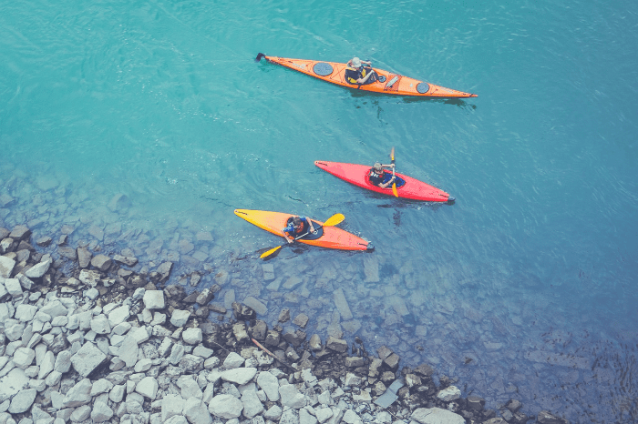 three people kayaking in different kayaks.