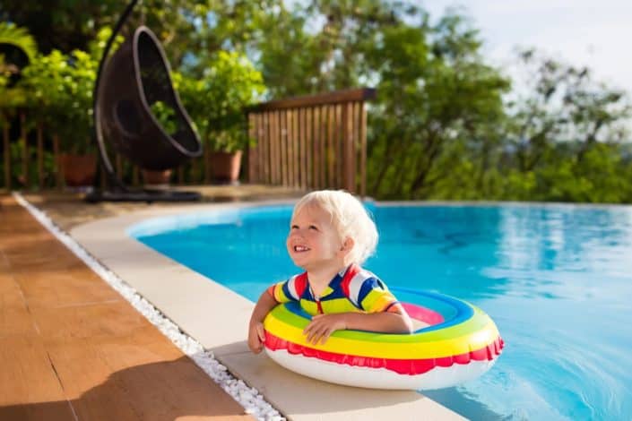 Picture of a kid in the swimming pool, wearing a buoy.